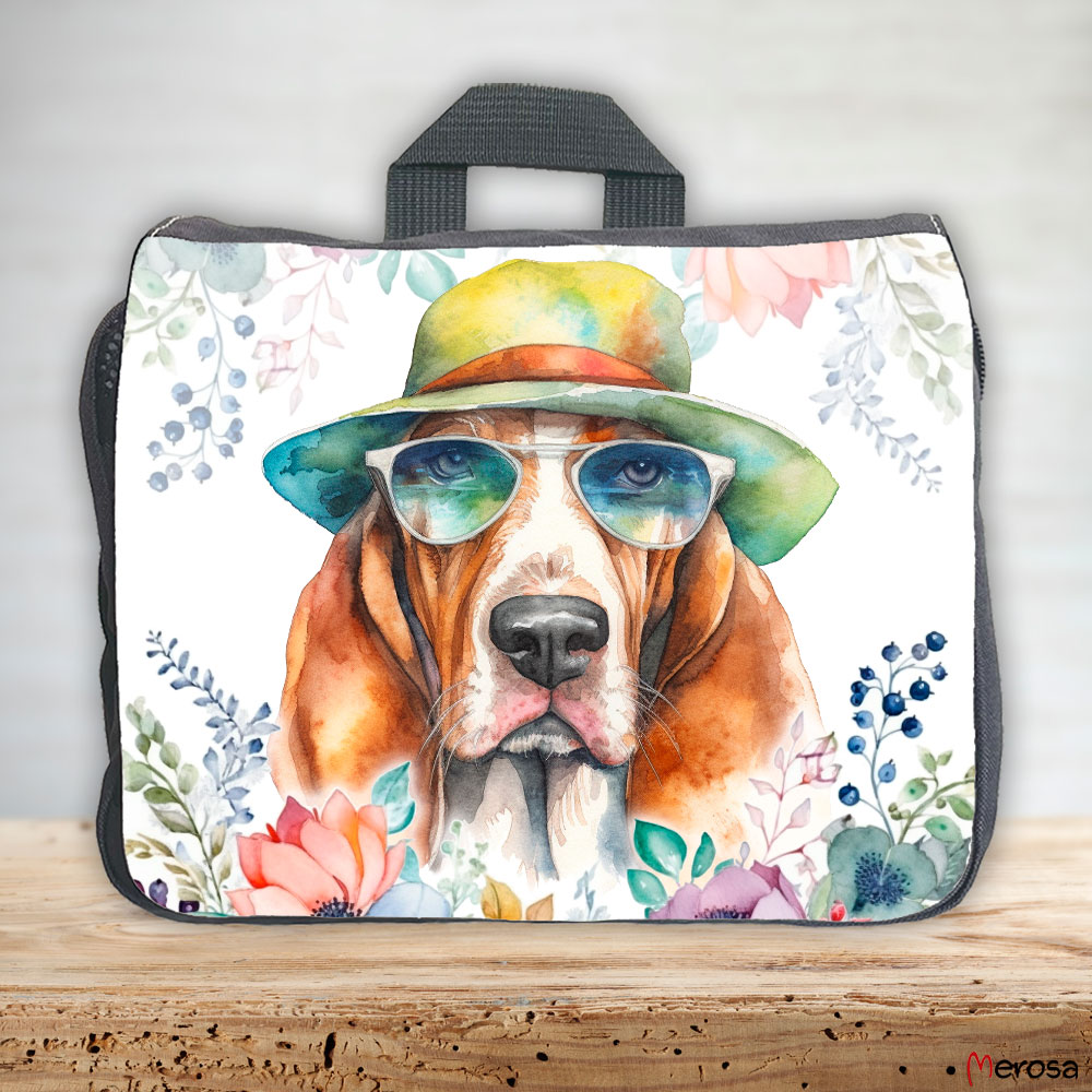eine anthrazitfarbene Hundetasche mit mehreren Reißverschlussfächern, welche mit einem Basset Hound mit Brille und Hut und einer Blumenranke im fröhlich bunten Watercolor-Stil bedruckt ist