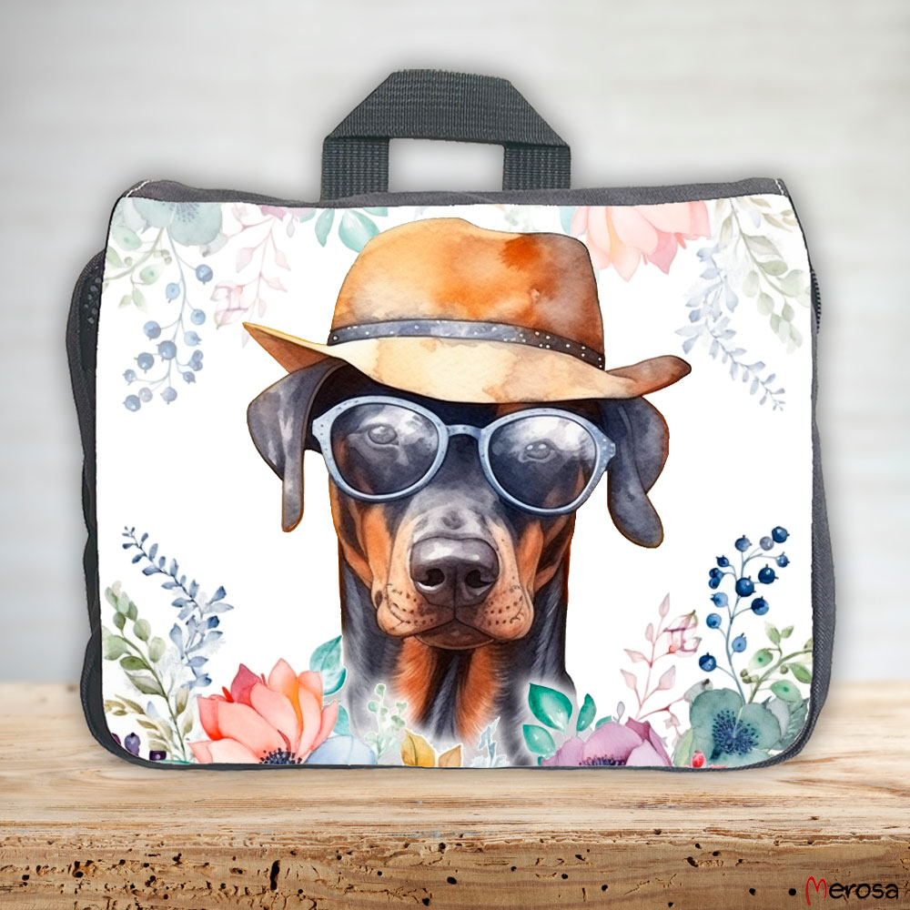 eine anthrazitfarbene Hundetasche mit mehreren Reißverschlussfächern, welche mit einem Dobermann mit Brille und Hut und einer Blumenranke im fröhlich bunten Watercolor-Stil bedruckt ist